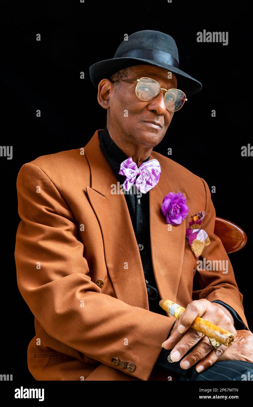 Man seated dressed as 1950s dandy or gangster with fedora hat and big cigar, Havana, Cuba, West Indies, Caribbean, Central America Stock Photo