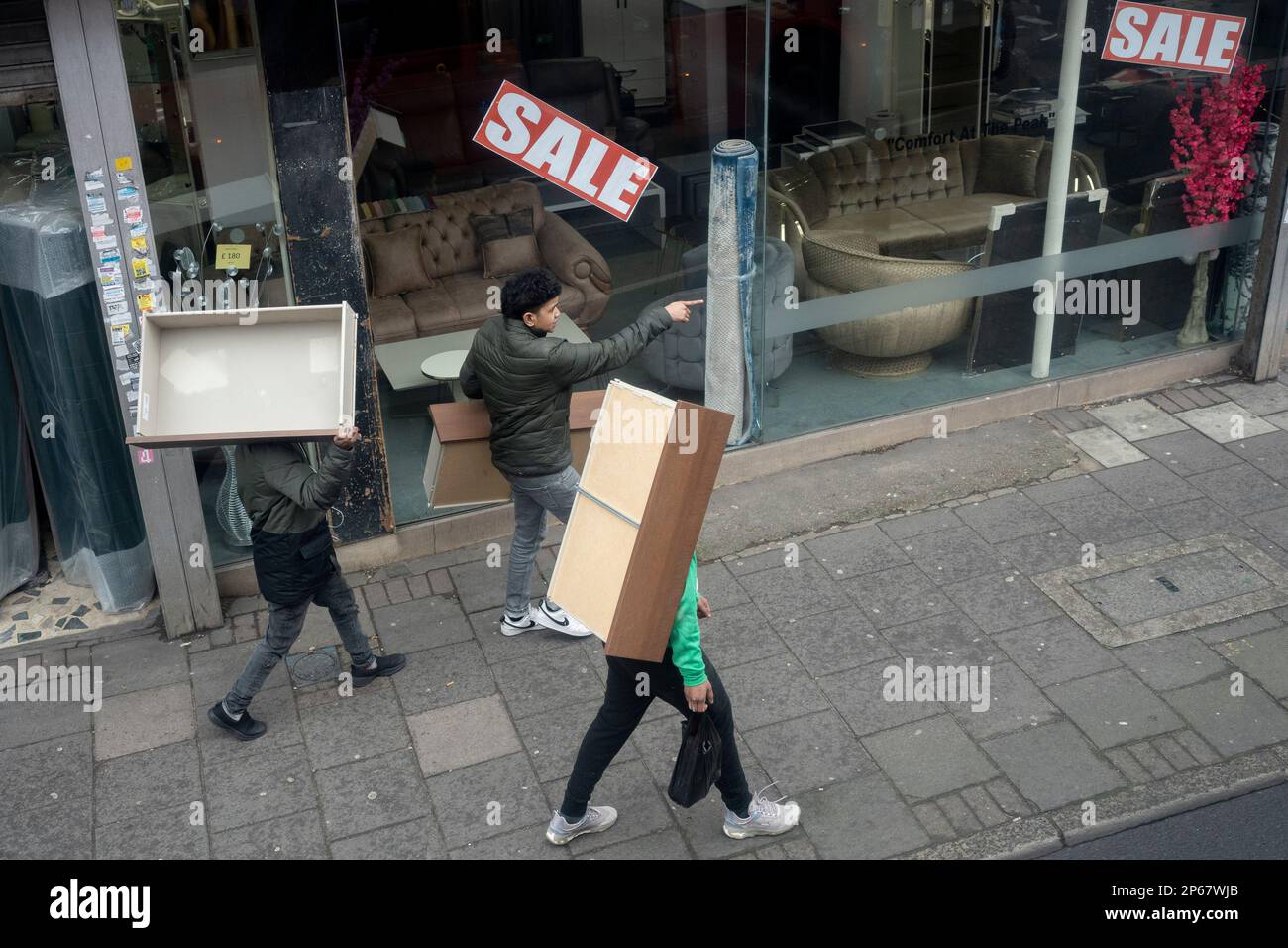 Three men each carry a piece of furniture, drawers for a home somewhere, down the Walworth Road in Camberwell, south London, on 7th March 2023, in London, England. Stock Photo