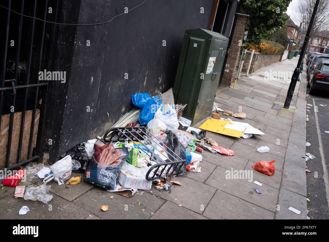 Packaging litter and food waste is spread across the pavement in a Cricklewood side street, on 6th March 2023, in London, England. Stock Photo