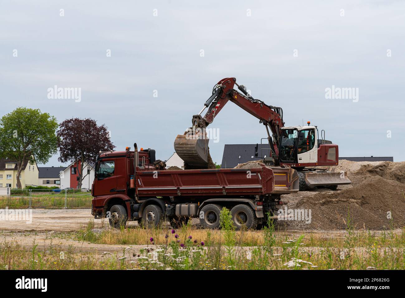 Brown excavator loading gravel into a truck at a construction site Stock Photo Alamy