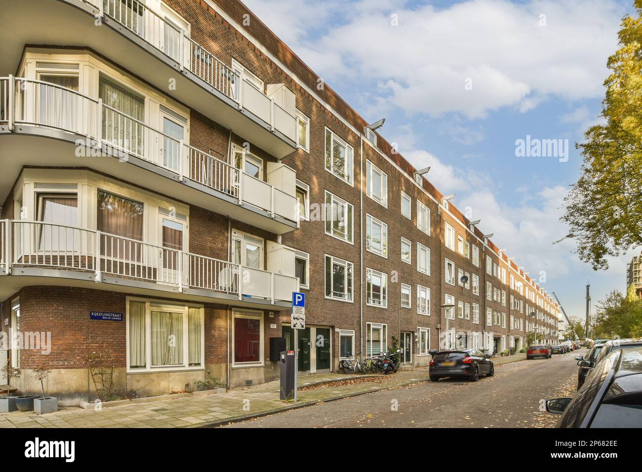 a city street with cars parked on the side and buildings in the back ...