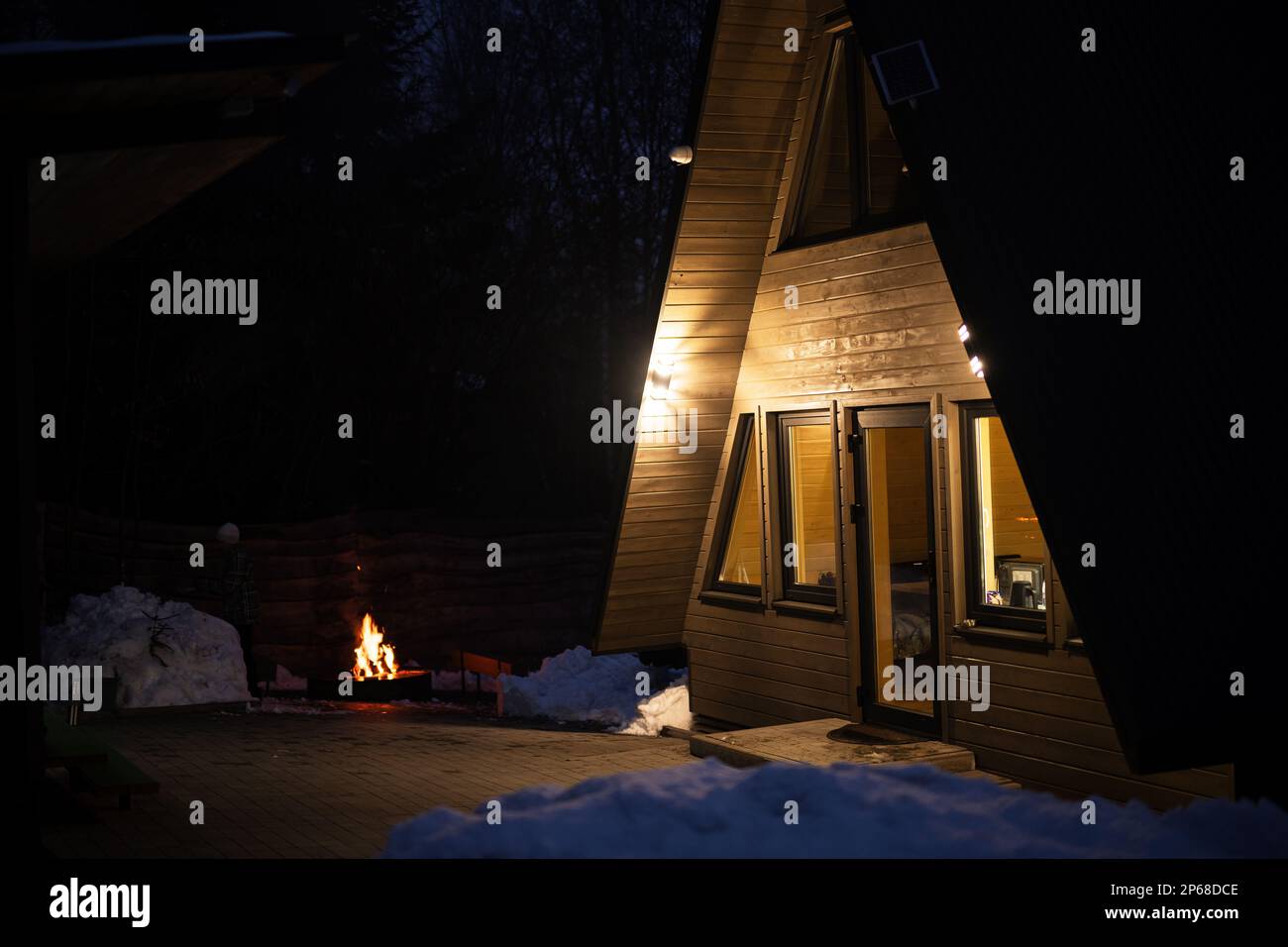 Exterior at dusk of modern triangle log cabin in the mountains with ...