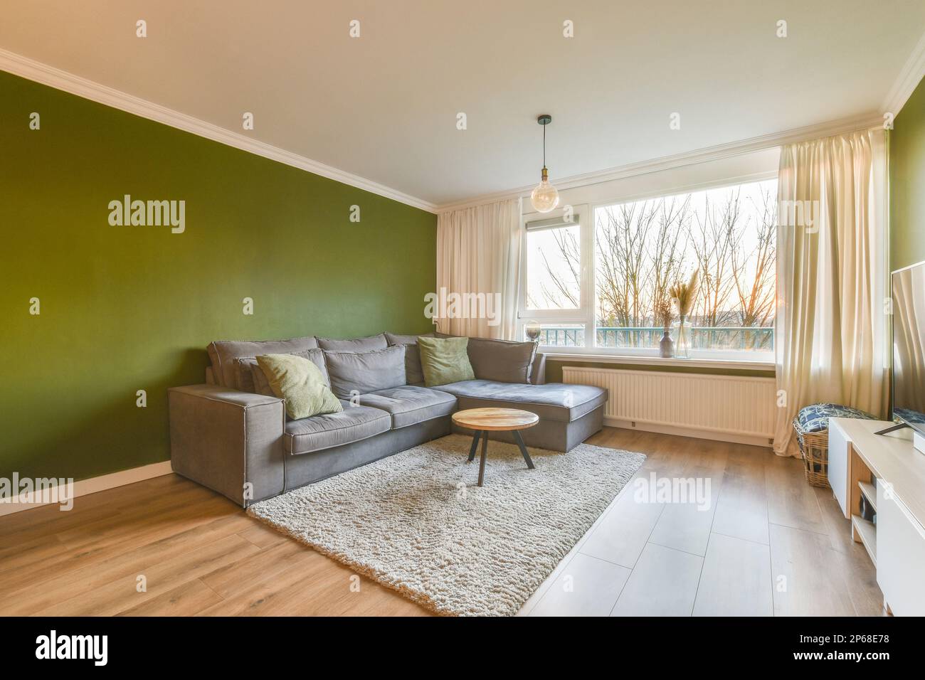 a living room with green walls and wood flooring on the wall, there is ...