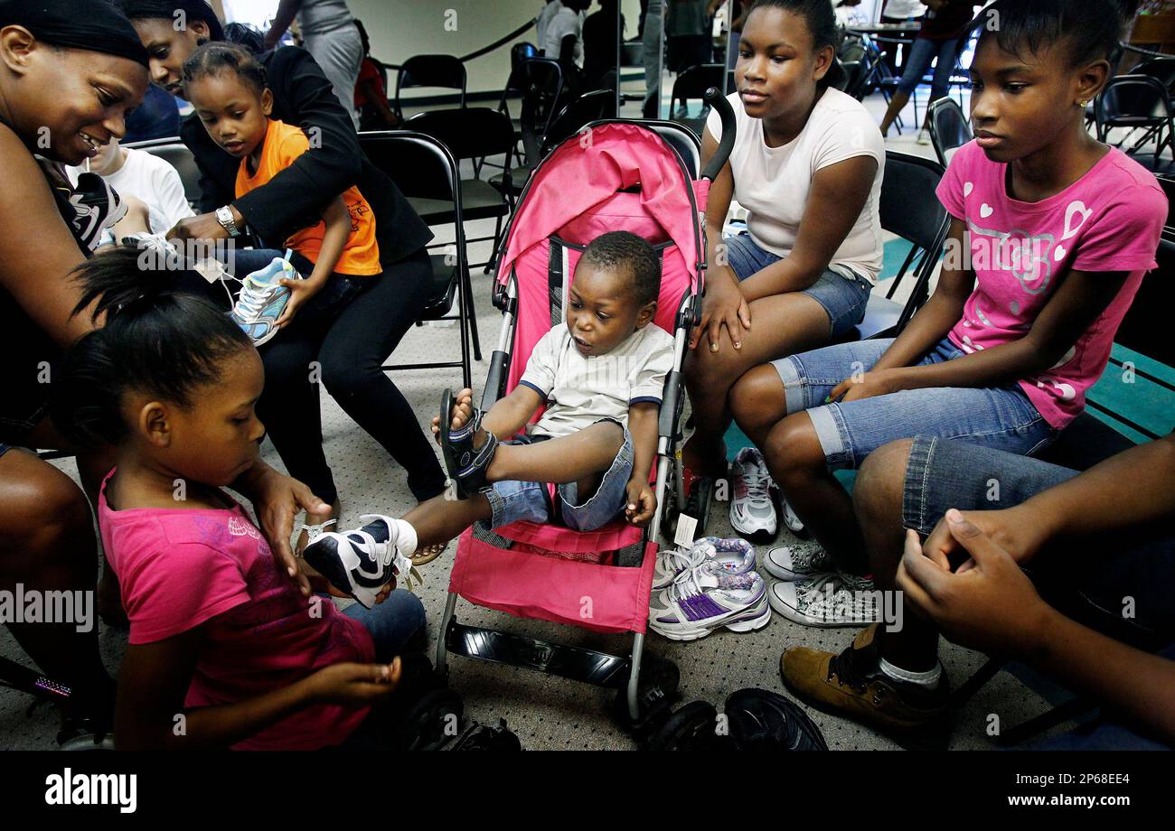 Sha'Marian Miller, 2, center, can't wait to get off his old sandals while  trying on new shoes with family members during the Back-to-School New Shoes  Ministry event at St. Andrews AME Church's