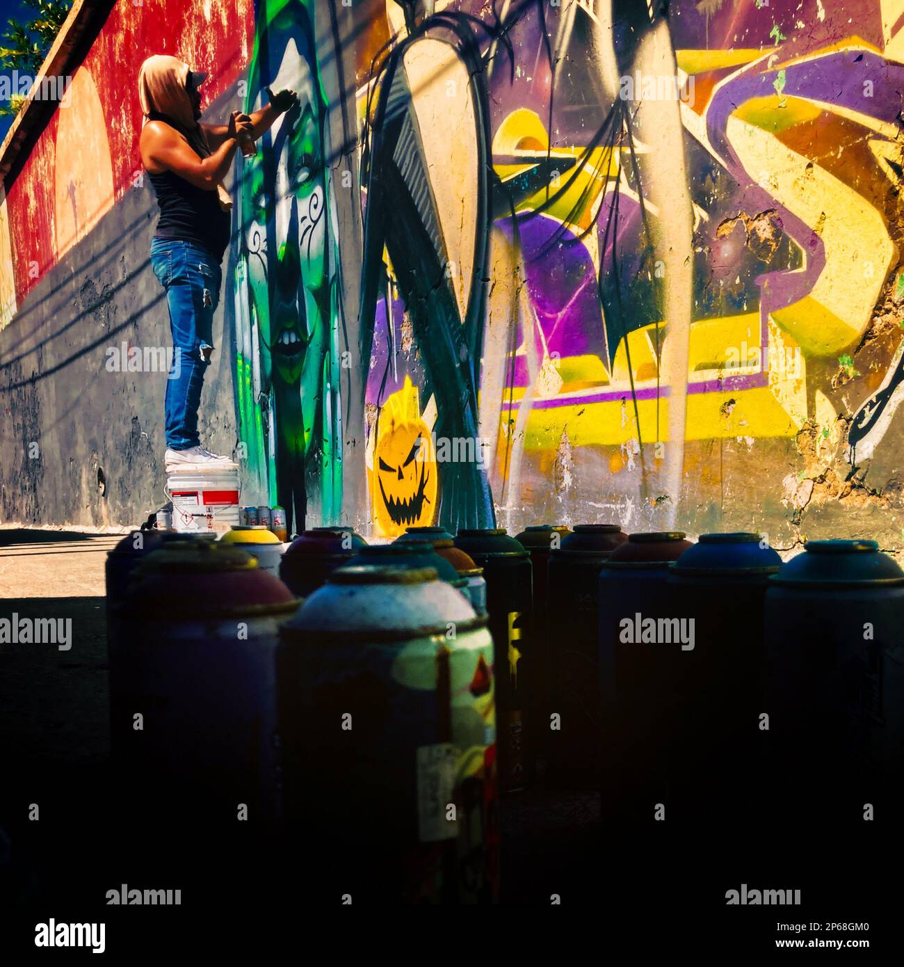 A Mexican street artist paints graffiti on the wall of a cemetery