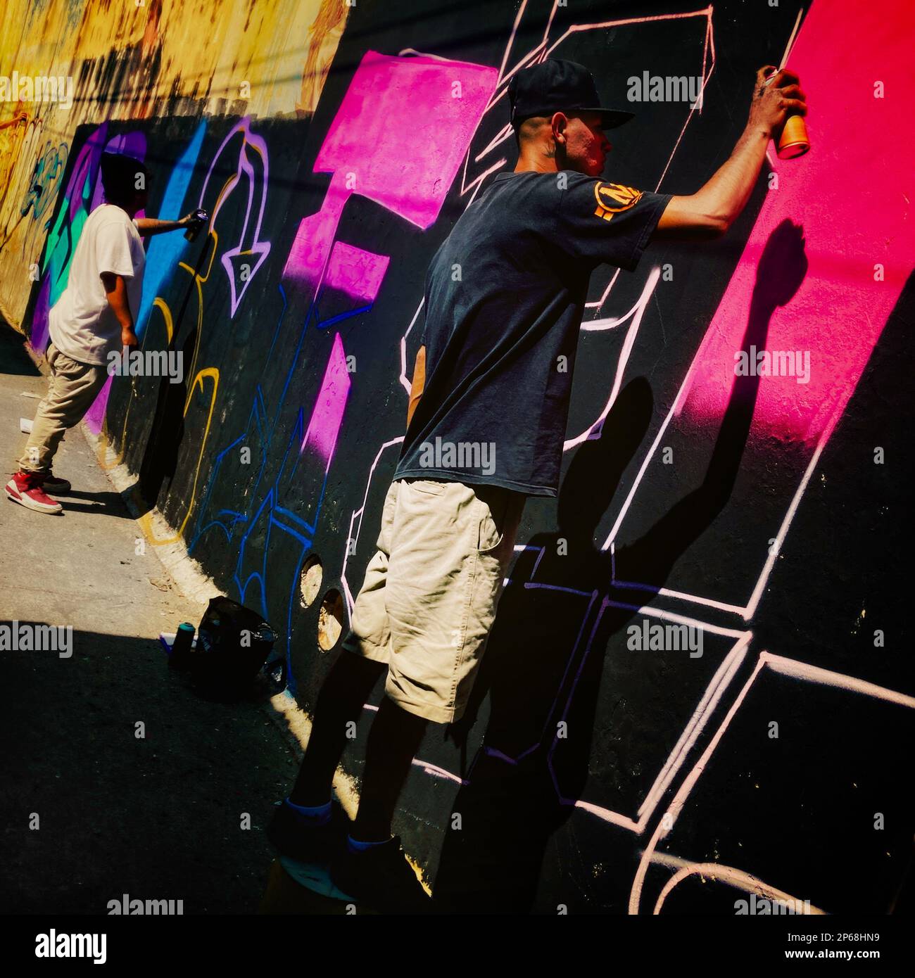 Mexican street artists paint graffiti on the wall of a cemetery during