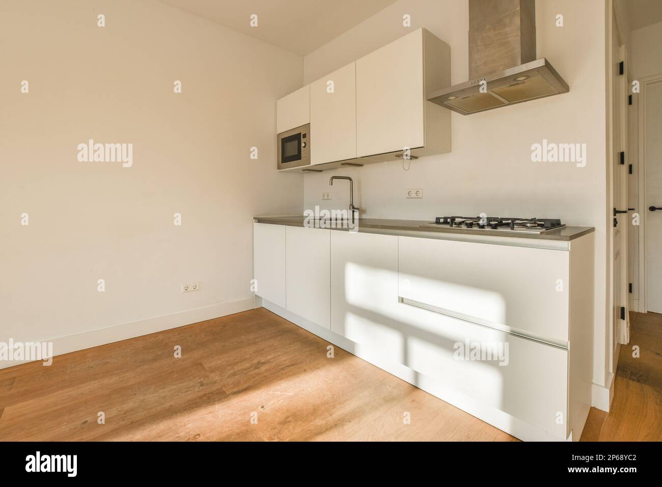 a kitchen with white cabinets and wood floors in an empty room that ...