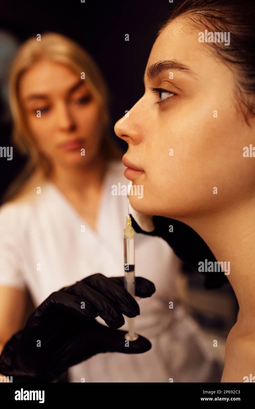 Beauty injections. Female cosmetologist in transparent gloves makes an