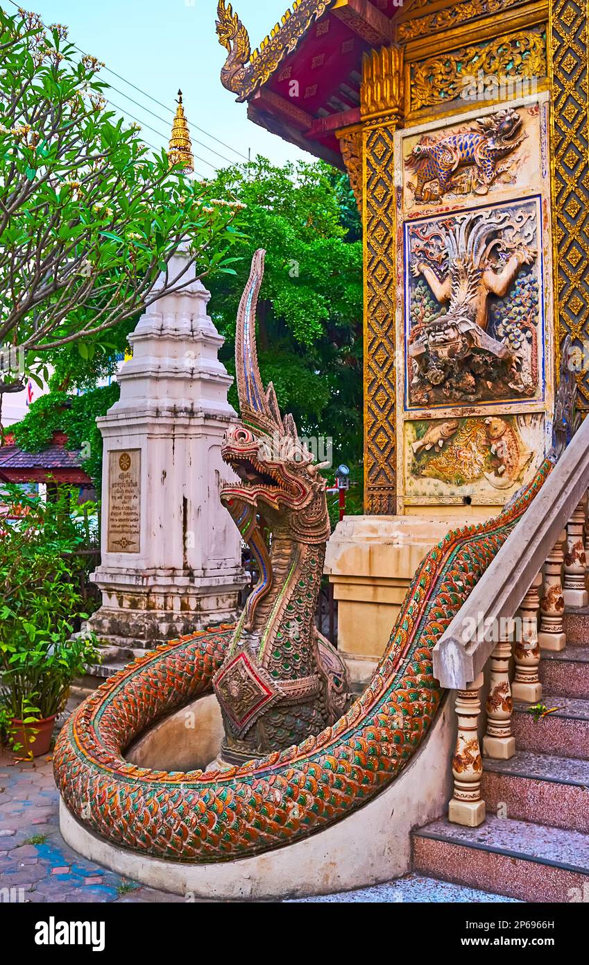 The colored stucco statue of Naga serpent guardian at the entrance to the ubosot of Wat Ket Karam and the wall sculptures of Kilin mythic creature and Stock Photo