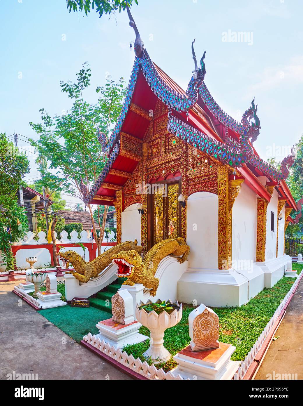 The splendid Lanna style Ubosot of Wat Umong Mahathera Chan with Mom statues, golt carvings, pyathat roof, Naga serpents on bargeboards, Chiang Mai, T Stock Photo
