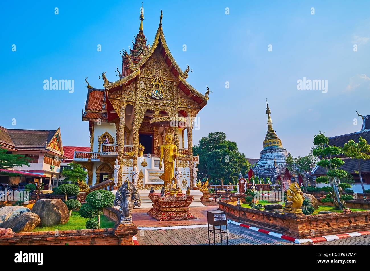 The richly decorated viharn-library of Wat Buppharam with carved gilt columns, gable end, pyathat roof and statues of Nagas, Devatas and Moms, Chiang Stock Photo