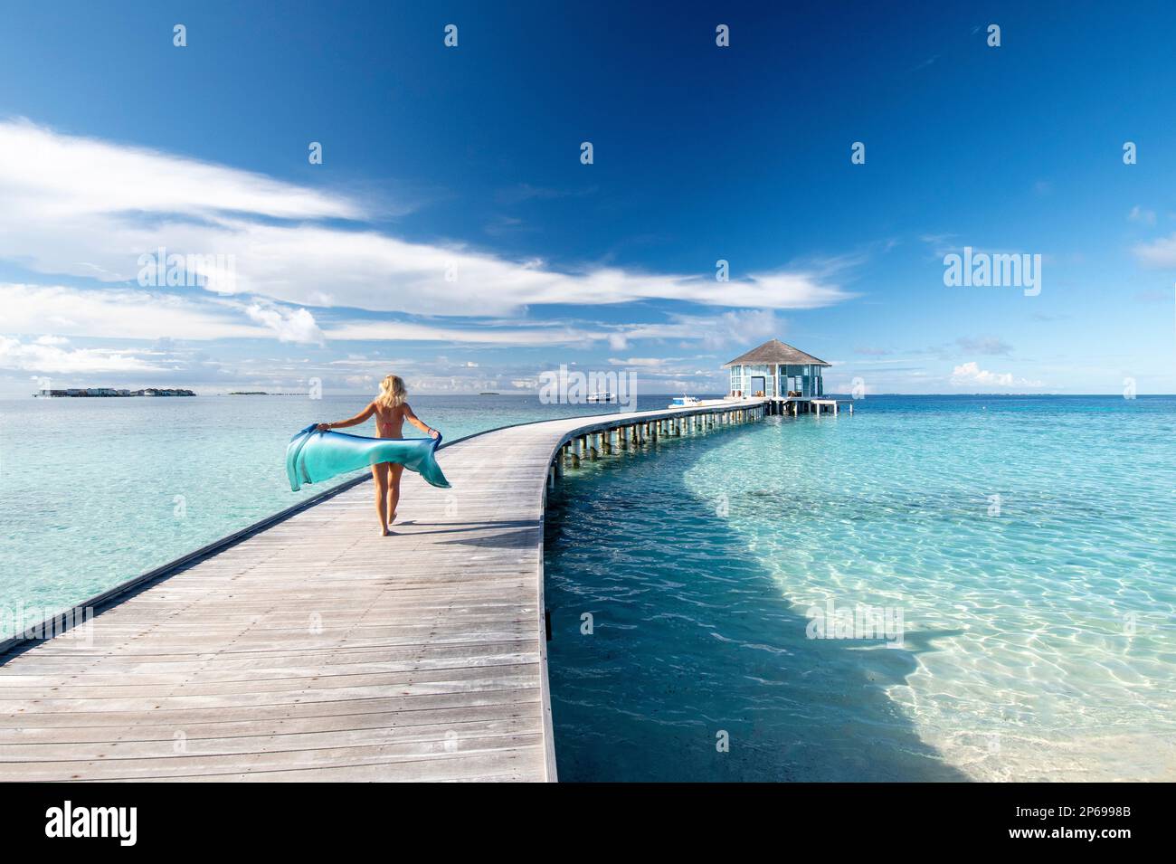 Young woman with a sarong walking on the wooden jetty of a Maldivian resort Stock Photo