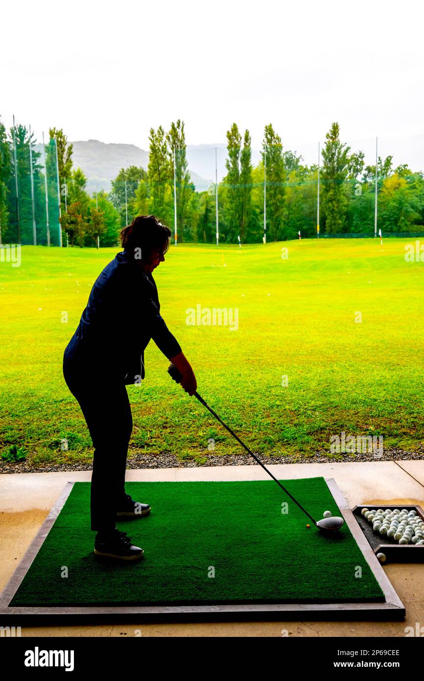 Golfer Training Her Golf Club Driver on Driving Range in a Rainy Day in