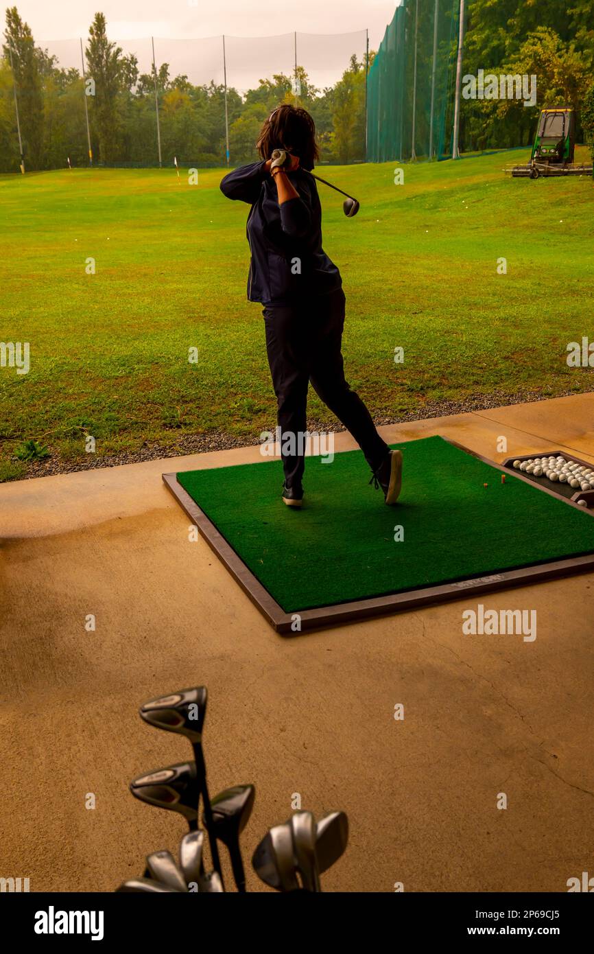 Golfer Training Her Golf Club Driver on Driving Range in a Rainy Day in