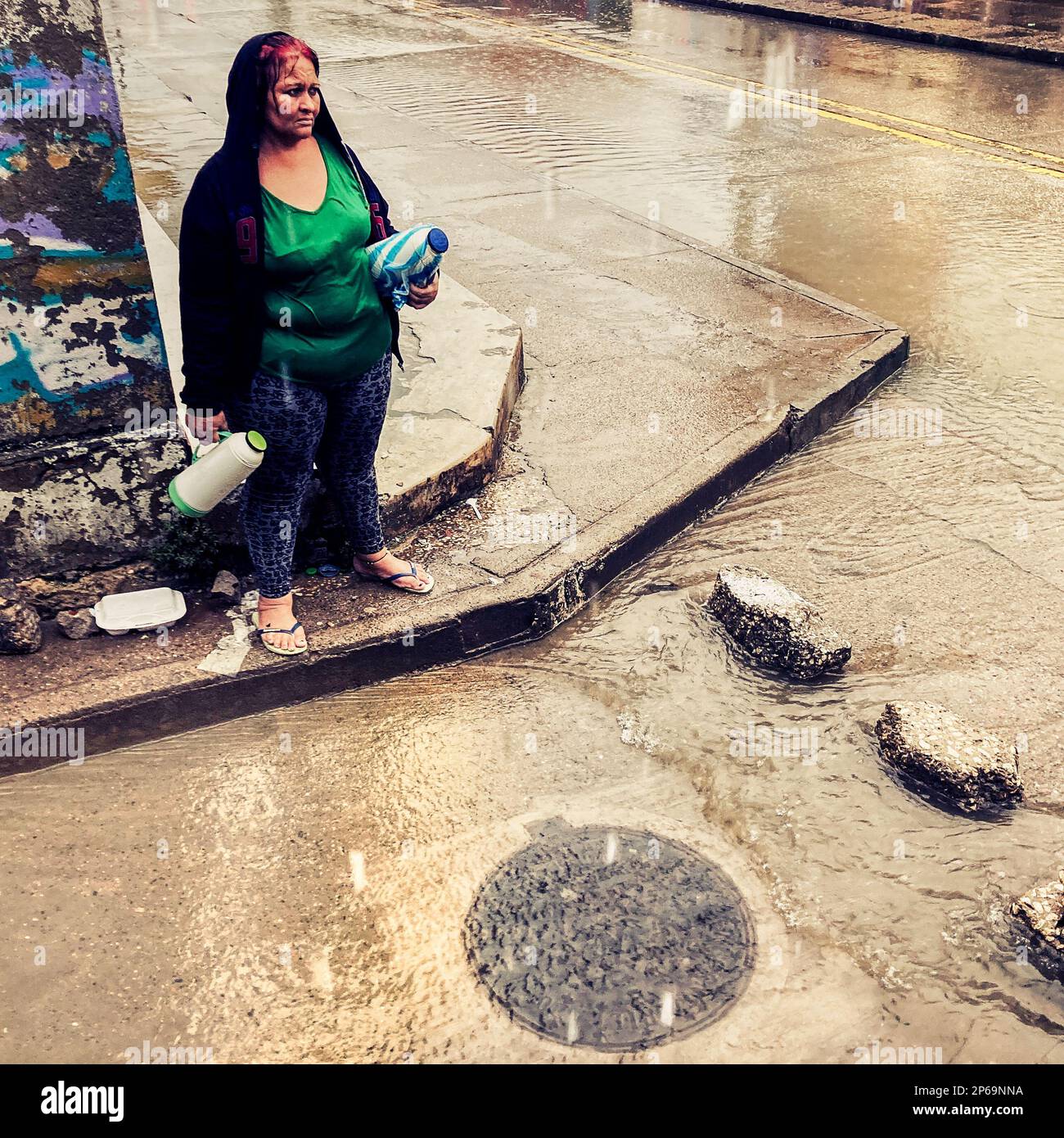 A Colombian coffee vendor crosses a street flash flooded by a heavy ...