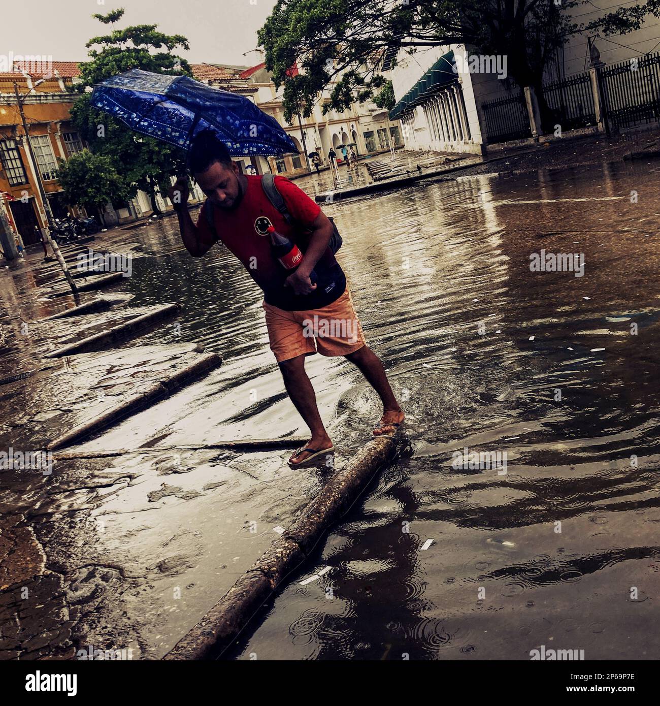 An Afro-Colombian man walks across the street flash flooded by torrential rain during the annual rainy season in Cartagena, Colombia. Stock Photo