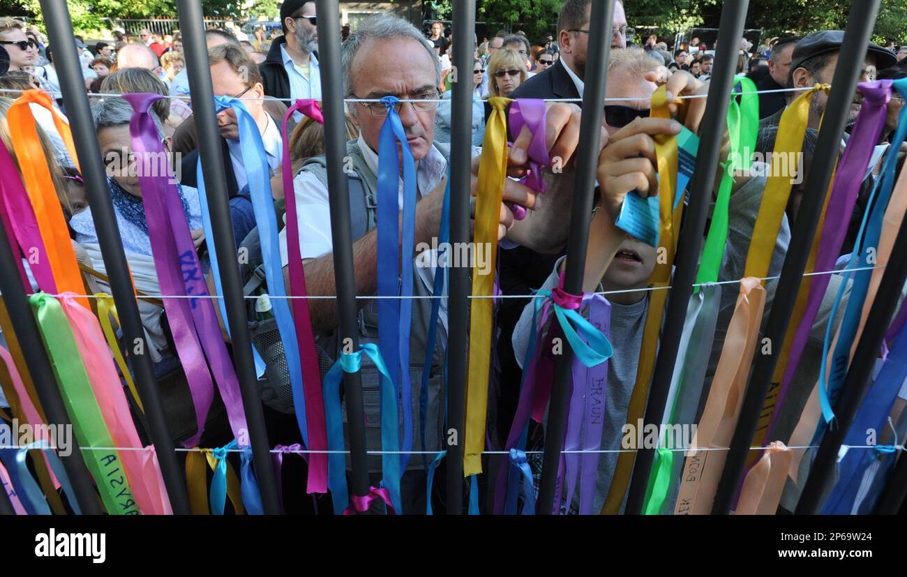 People attach ribbons with Jewish names onto the fence of a former