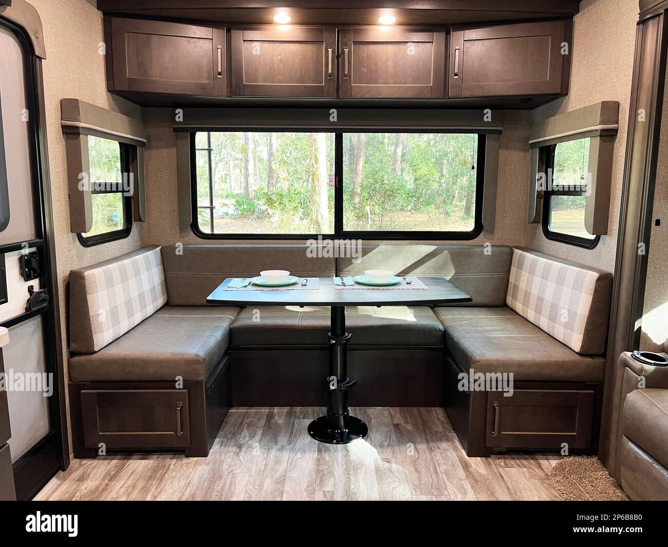 Perfect for remote work, the modern, clean design of this fifth wheel travel trailer shows the dining area with storage and a huge picture window. Stock Photo