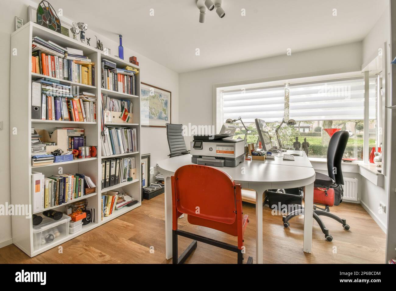 a home office with lots of books on the shelves and a red chair in ...