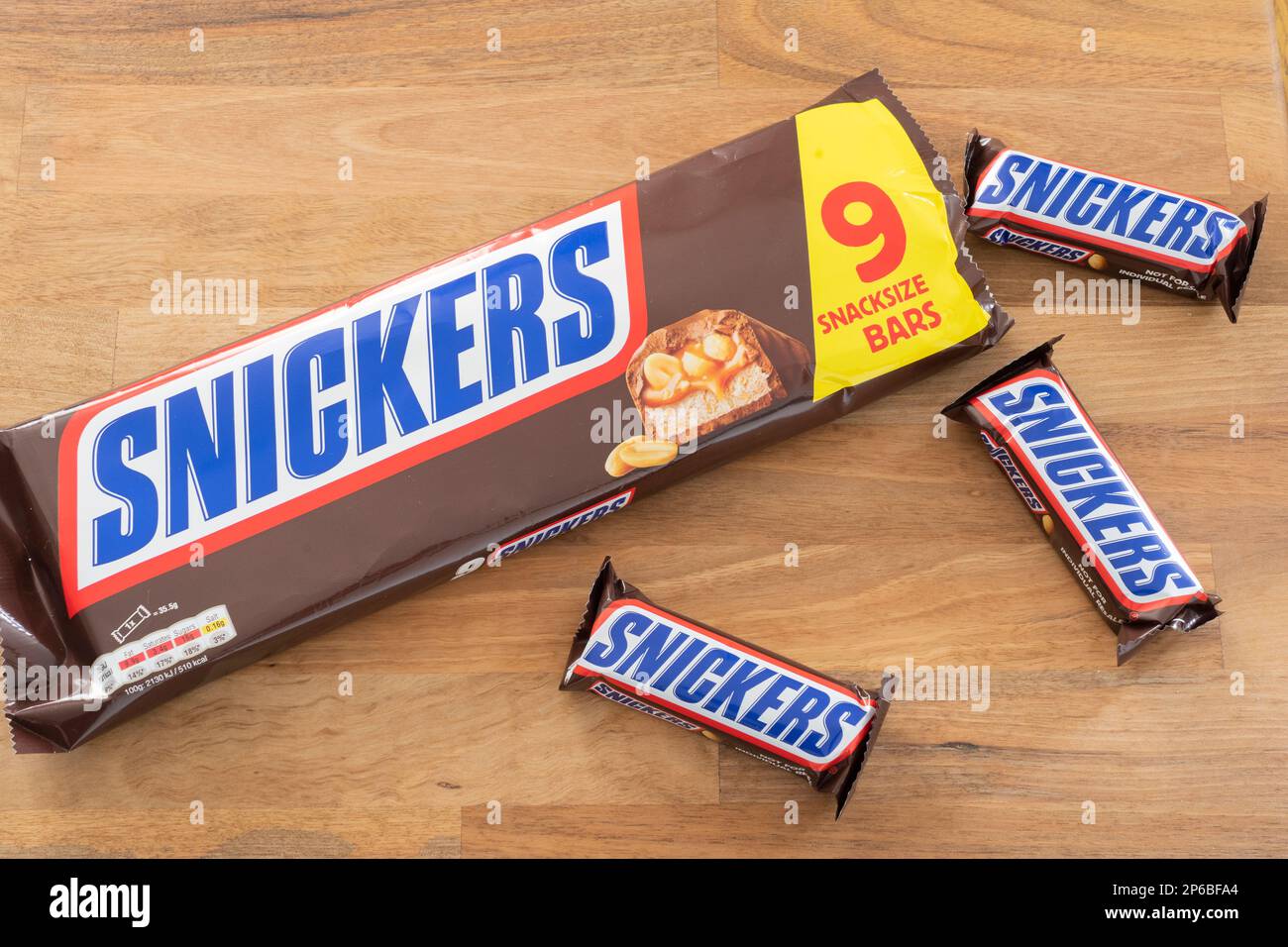 Snickers bars and a snickers packet. Snickers is owned by Mars, Incorporated. Theme: snacking, snack food, unhealthy eating, chocolate bar industry Stock Photo