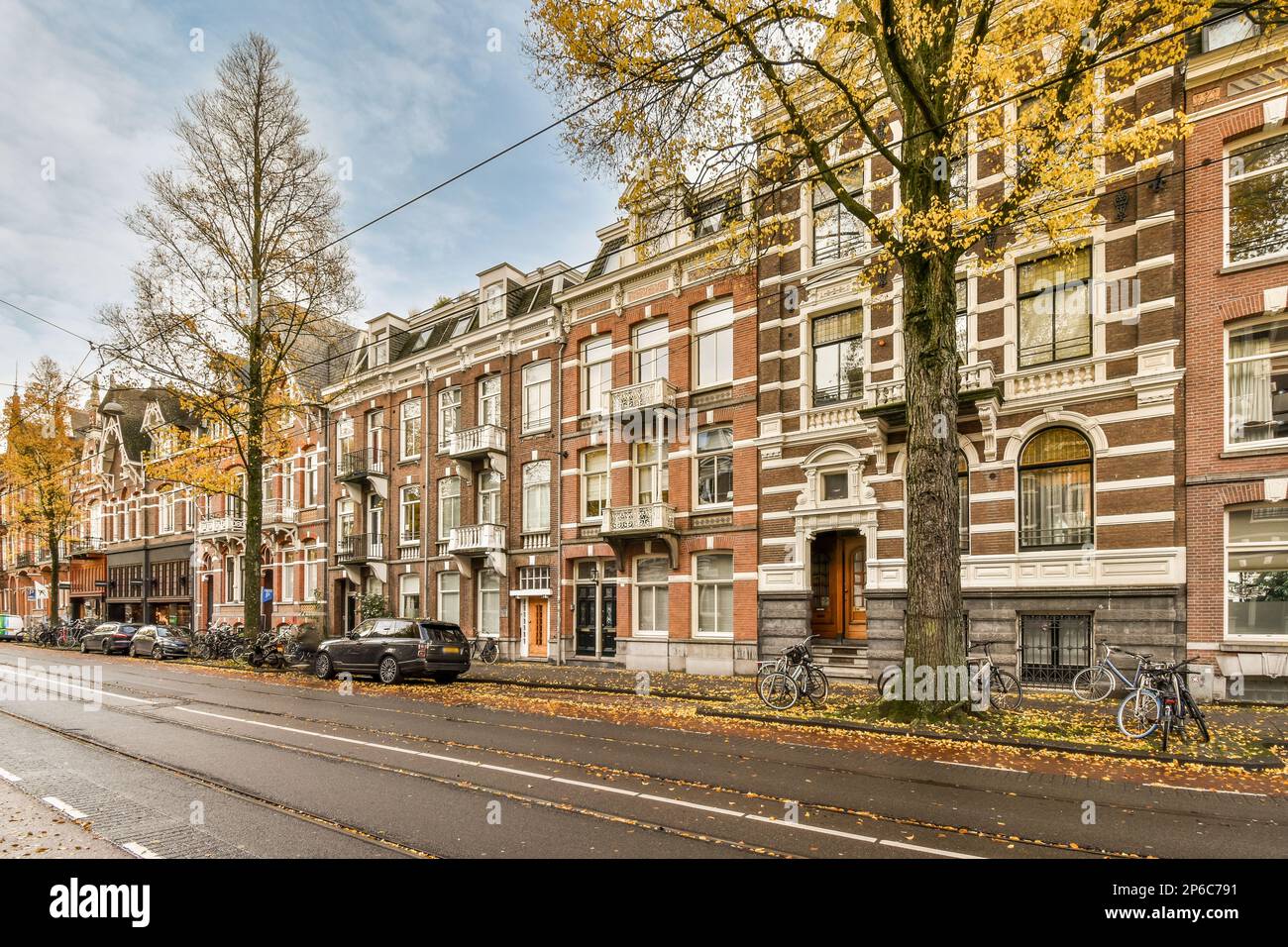 a city street with parked cars and bicycles on the side of the road in front of an old brick