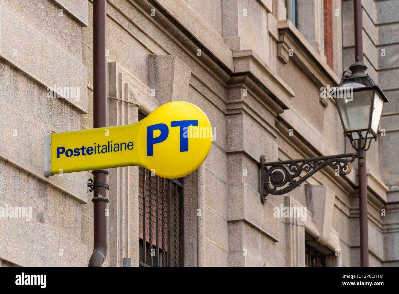 Cuneo, Italy - April 11, 2022: PT Poste Italiane, Italy Post logo on yellow sign near ancient lamppost , outside the Italian post office. Tex: Posteit Stock Photo