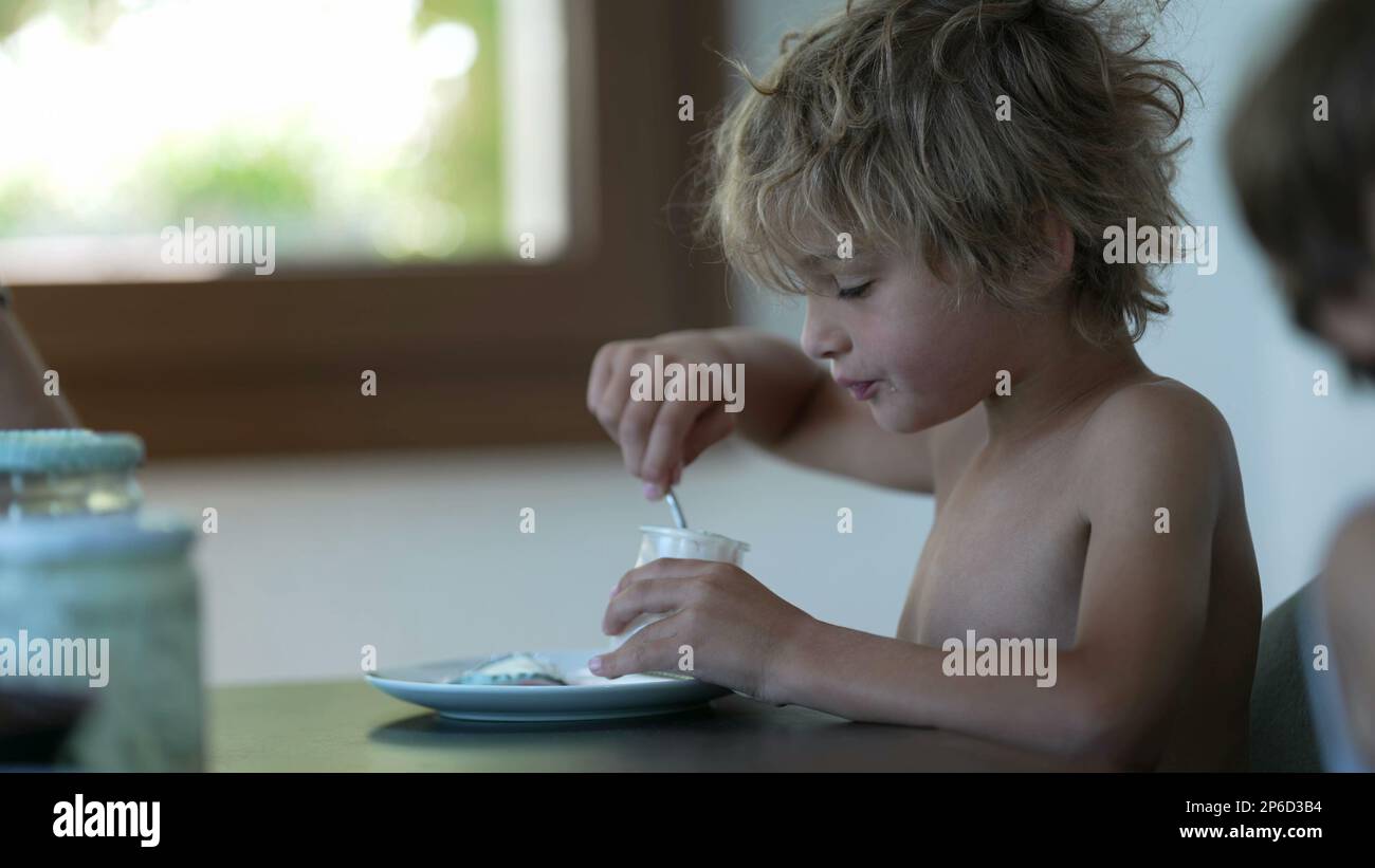 Candid kid stretching arms in morning after eating yogurt at breakfast