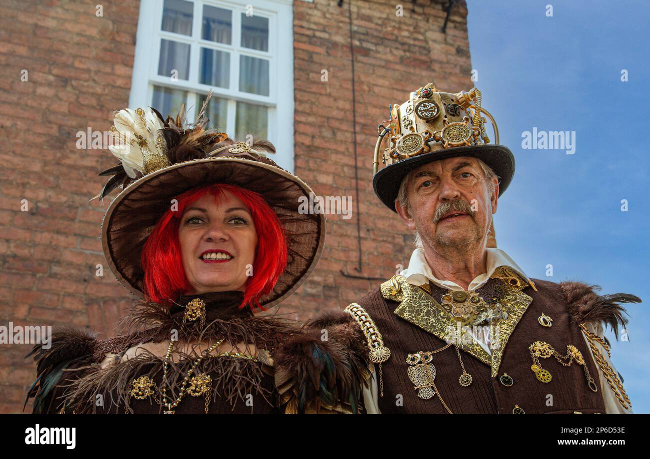 Portrait of a middle aged steampunk couple standing in front of a house. Stock Photo