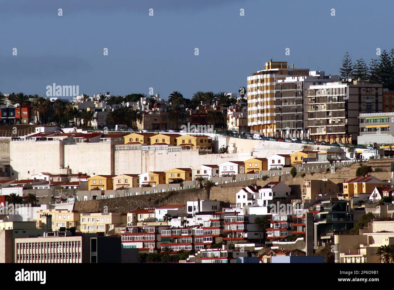 A row of houses built on an hillside giving the illusion of comical faces (with the upper storey windows as eyes) peering over a wall in Grand Canaria. Stock Photo