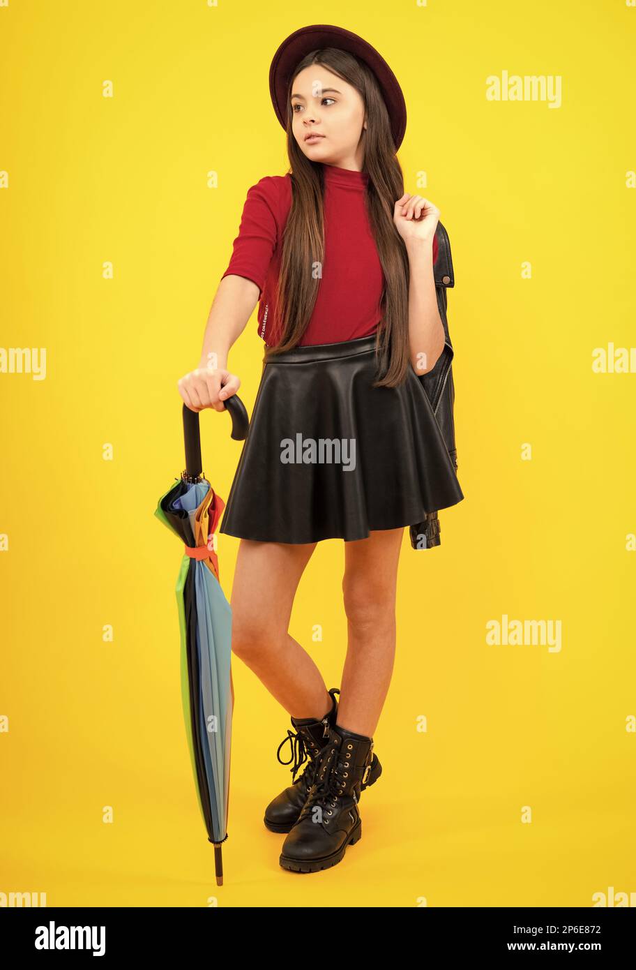 Fashion autumn kids weather. Child teenager girl with rainbow umbrella in autumn black leather skirt boots and hat isolated on yellow studio Stock Photo Alamy