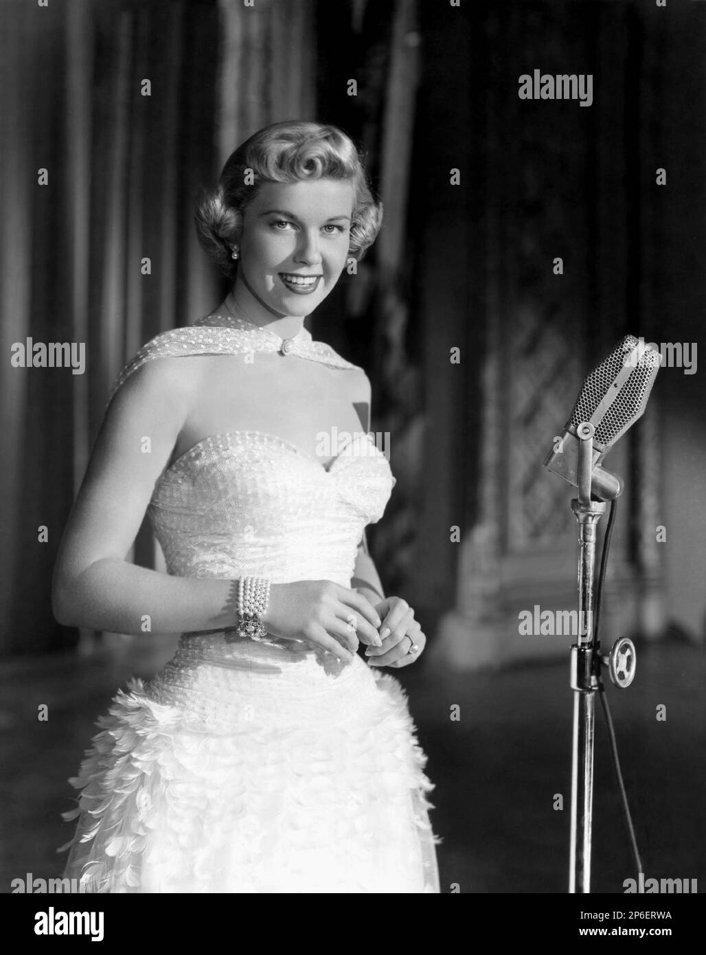 1953 ca  : The actress and singer DORIS DAY ( real name Doris Mary Ann Kappelhoff , born 3 April 1924 Cincinnati, Ohio, USA ) in a pubblicity movie still   - FILM - MOVIE - attrice cimatografica - blonde - bionda - scollatura - decollete' - neckopening - microfono - microphone - braccialetto - bracelet - pearls - perle - jewels - jewellery - gioiello - gioielli - bijoux - smile - sorriso  ----  Archivio GBB Stock Photo