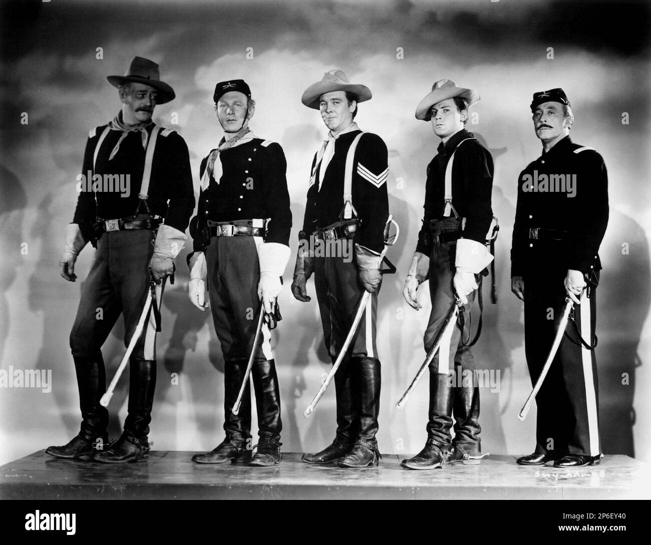 1948 : The  celebrated movie actors  JOHN WAYNE with GEORGE O'BRIEN (first from right)  in a pubblicitary shot for the movie SHE WORE A YELLOW RIBBON ( I cavalieri del Nord-Ovest ) by John FORD , from a novel by James Warner Bellah - CINEMA - ATTORE CINEMATOGRAFICO - COWBOY - WESTERN - hat - cappello -  FILM -spada - sword - foulard - bandanna - bandana - military uniform - uniforme divisa militare - gloves - guanti - cavalleria - booths - stivali  ----  Archivio GBB Stock Photo