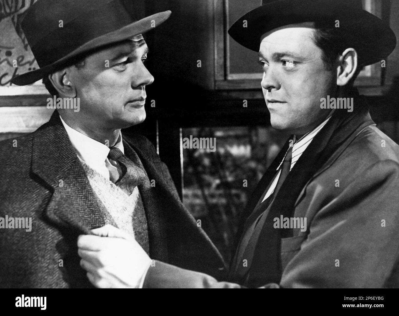 1949 : The  movie actor ORSON WELLES ( 1915 - 1985 ) with JOSEPH COTTEN  in a pubblicitary shot  for THE THIRD MAN ( Il terzo uomo ) by Carol Reed , from a novel by Graham Greene - FILM NOIR  - CINEMA - ATTORE CINEMATOGRAFICO - collar - colletto - hat - cappello - tie - cravatta -  cappotto - coat - FILM - TRILLER - SUSPANCE   - profilo - profile  - menace - minaccia ----  Archivio GBB      Archivio Stock Photo