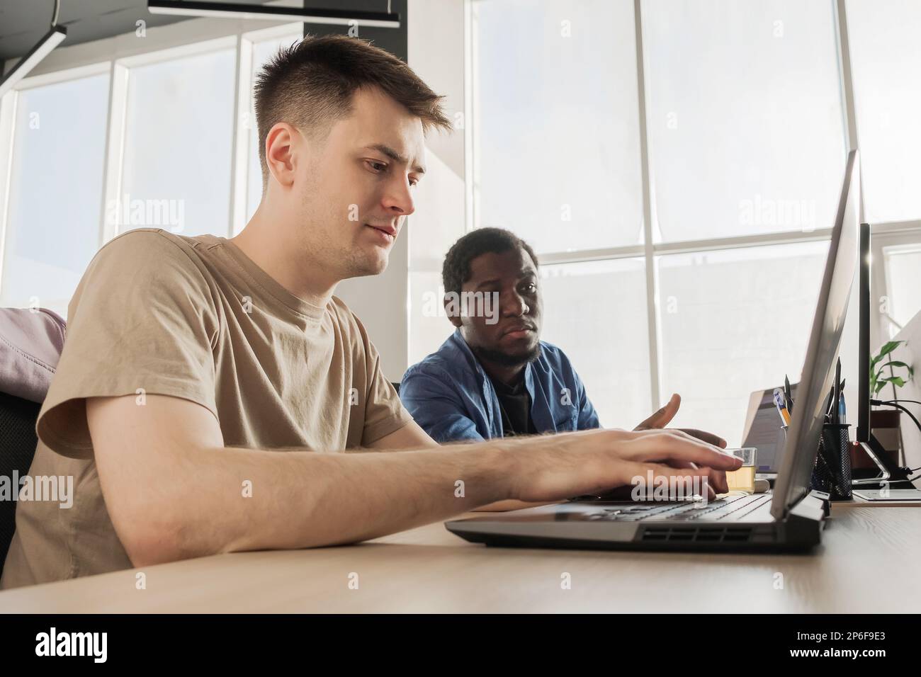 Two programmers working in the office of a software development company. Coding technologies, site design. Successful diverse Teamwork. Cyberspace Stock Photo