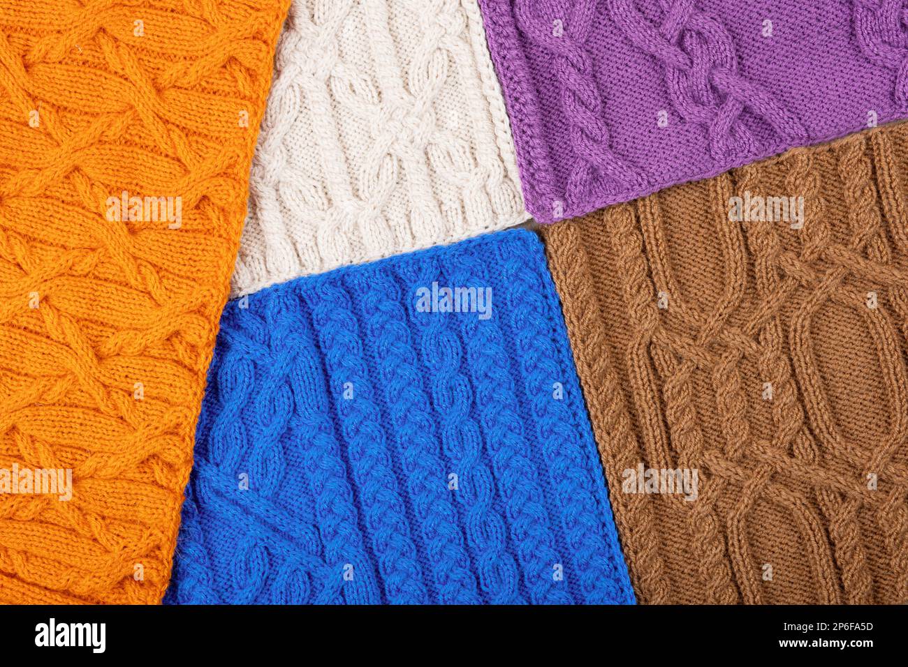 Knitted blue, lilac, brown, orange and beige background. Large knitted fabric with a pattern. Close-up of a knitted blanket. Banner Stock Photo