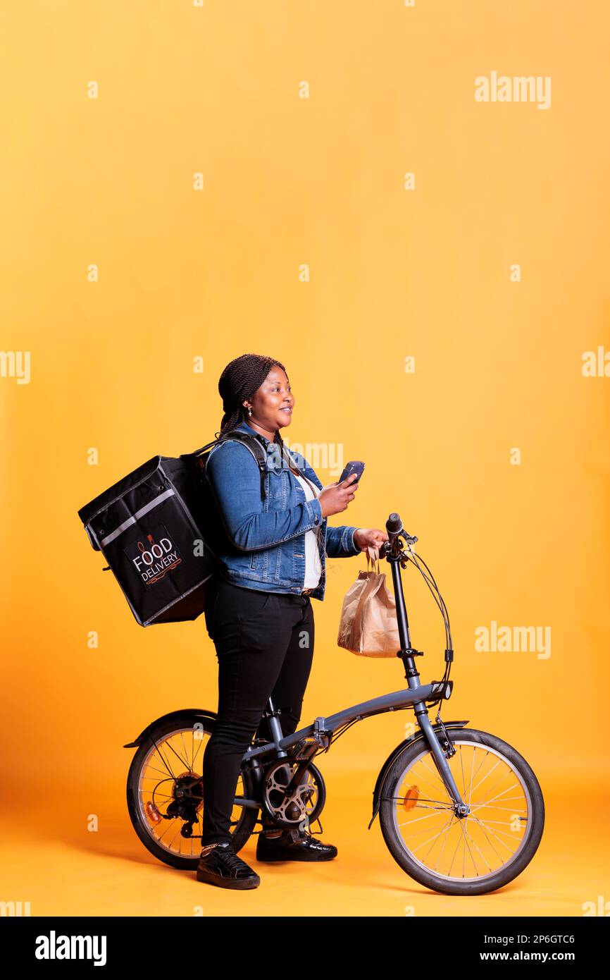 Deliverywoman holding smartphone checking client adreess on fast food ...