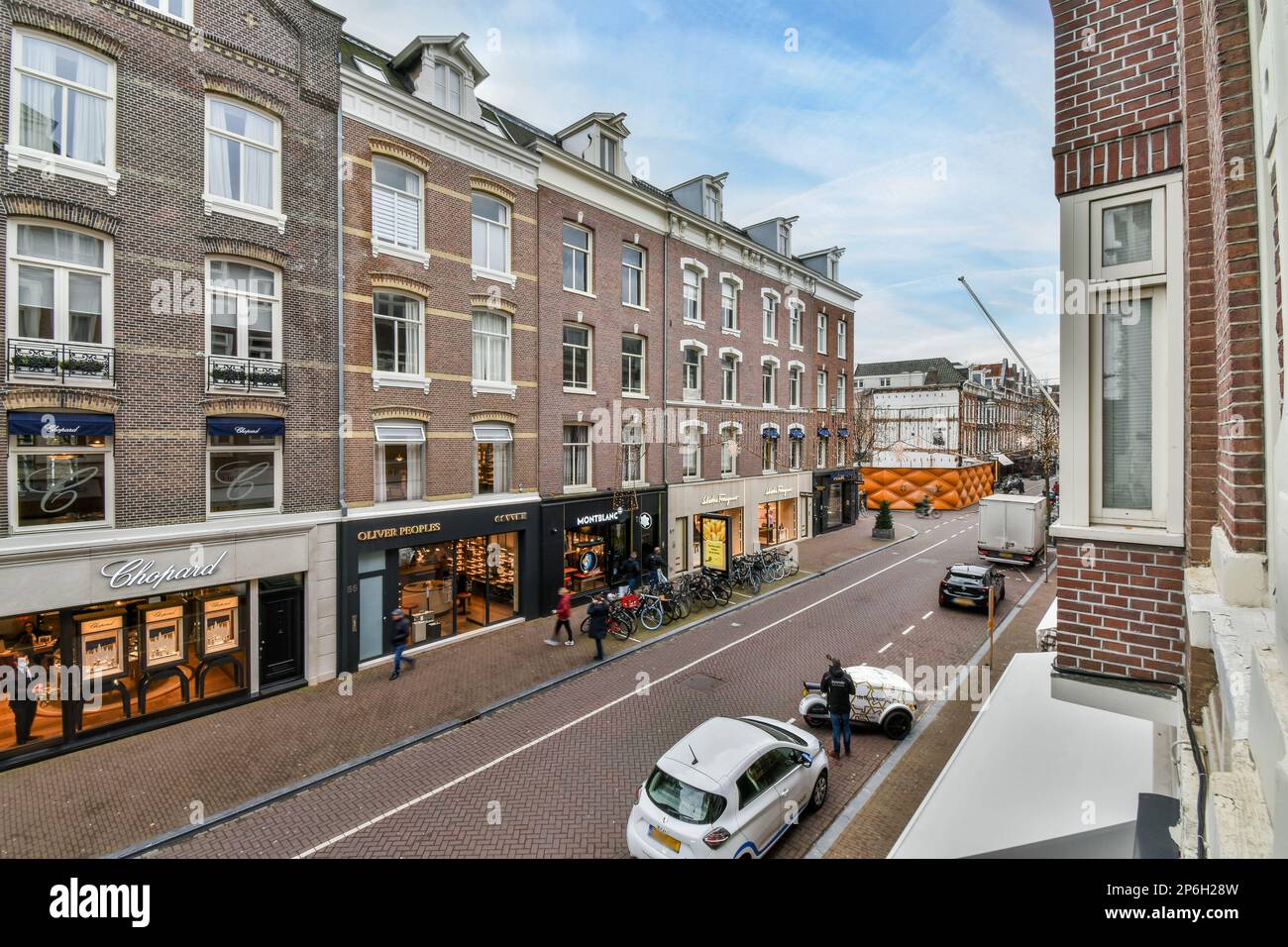 a city street with cars parked on the side and people walking down the ...