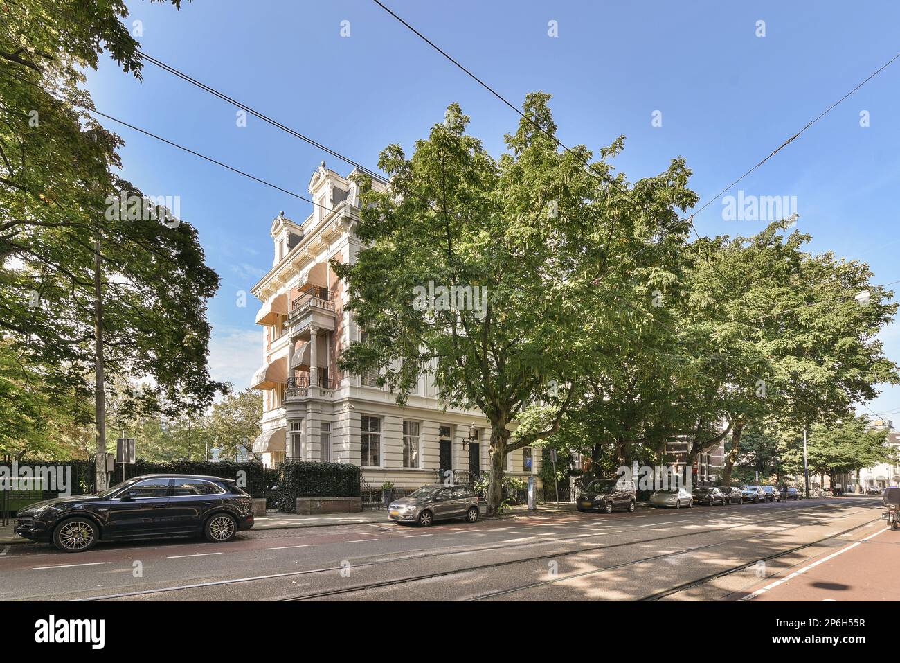 a city street with cars parked on the side of the road and trees lining ...