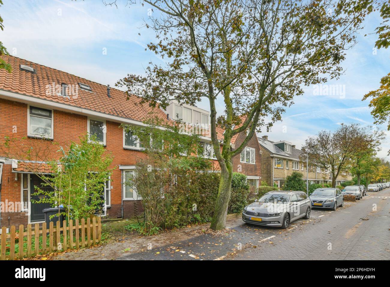 a street with cars parked on the side and houses in the back ground ...