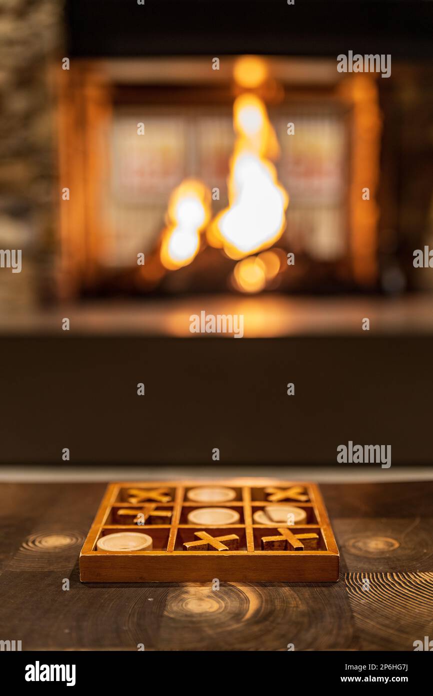A board for the game of Tic-tac-toe in front of a cozy fireplace Stock Photo