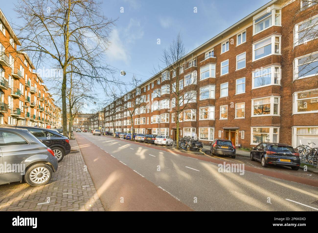 a city street with cars parked on the side and trees in the middle of ...