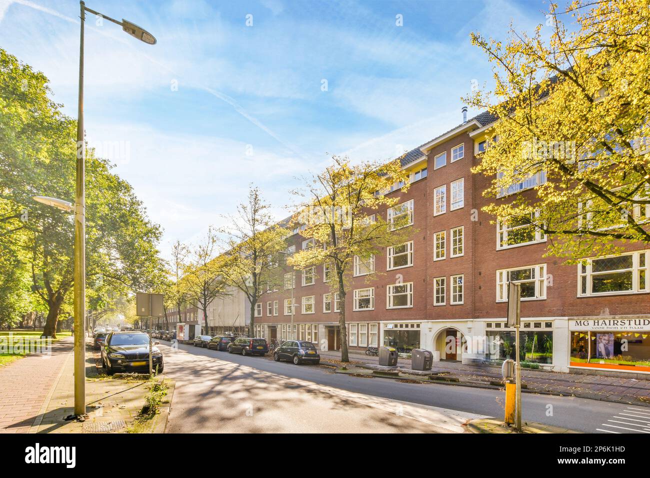 a city street with cars parked on the side and trees in the middle of ...