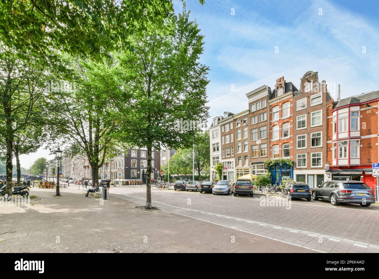 a city street with cars parked on the side and trees in the middle part ...