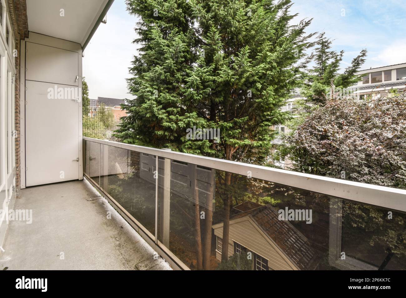 Amsterdam, Netherlands - 10 April, 2021: a balcony with a tree in the middle and some bushes on the other side, as well viewed from an apartment window Stock Photo