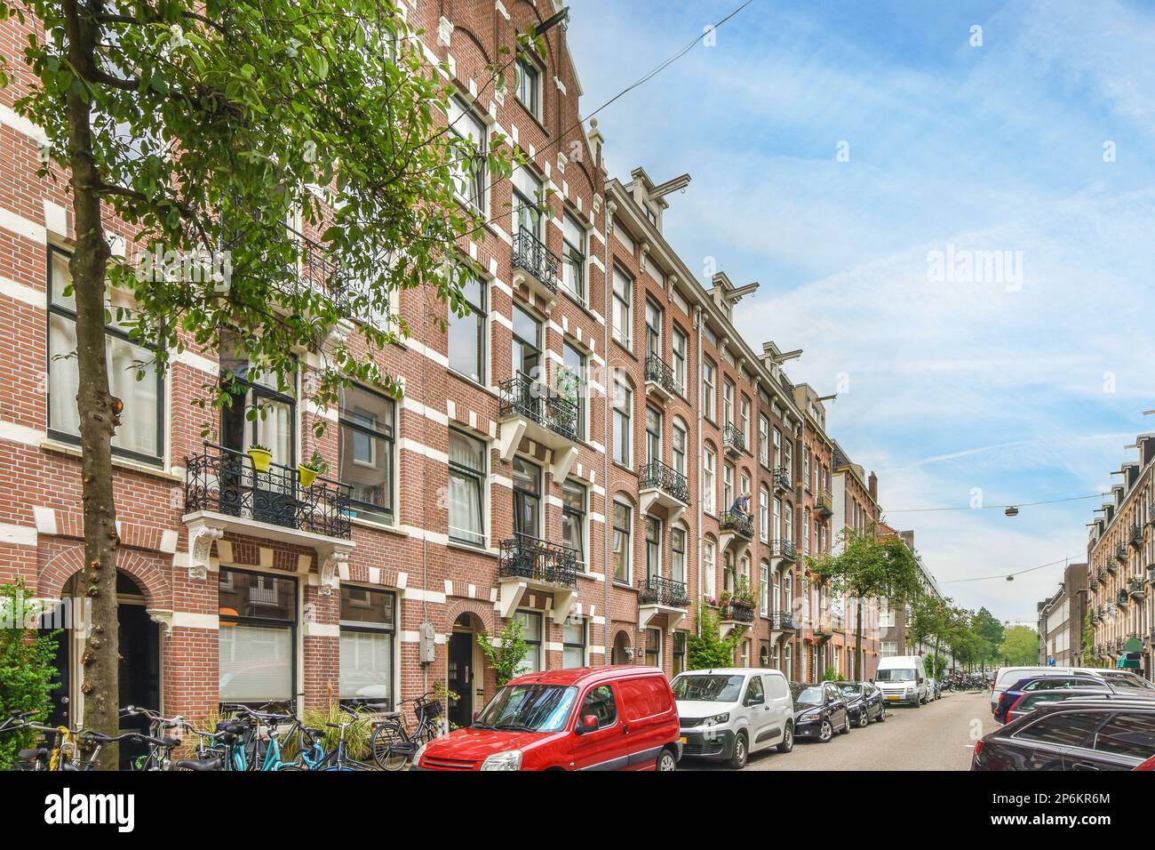 a street with cars parked on the side and people walking down the road ...