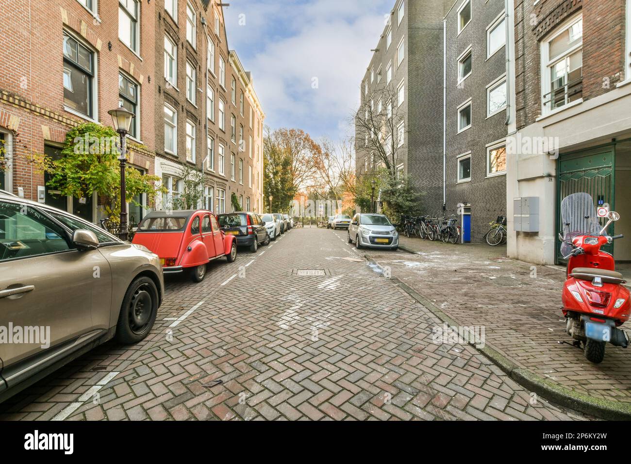 a city street with parked cars and scoots on the side of the road in ...