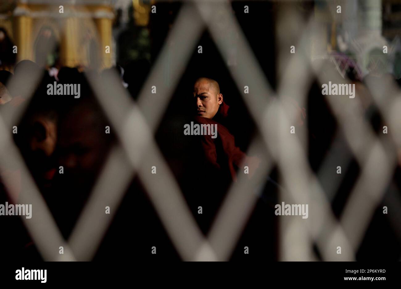 A Myanmar Buddhist monk is seen through steel railings during a prayer ...