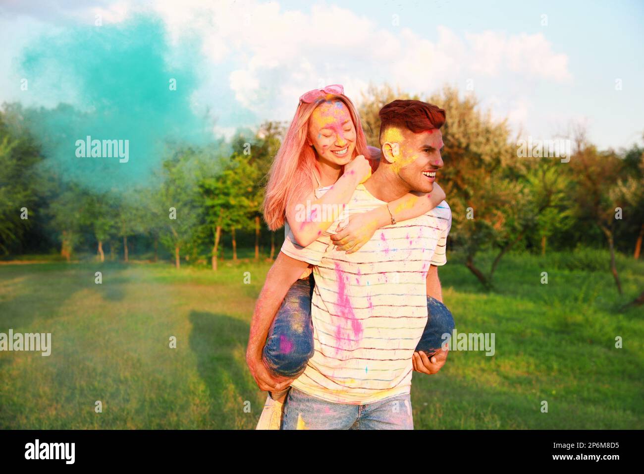 Happy couple covered with colorful powder dyes outdoors. Holi festival celebration Stock Photo