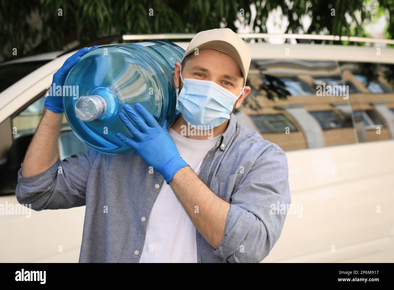 https://c8.alamy.com/comp/2P6M917/courier-in-medical-mask-holding-bottle-of-cooler-water-near-car-outdoors-delivery-during-coronavirus-quarantine-2P6M917.jpg