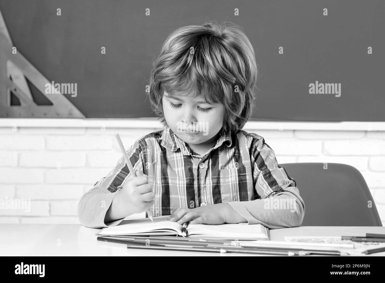 Child near chalkboard in school classroom. Happy school kids at lesson. Cute Preschool in Classroom. Stock Photo